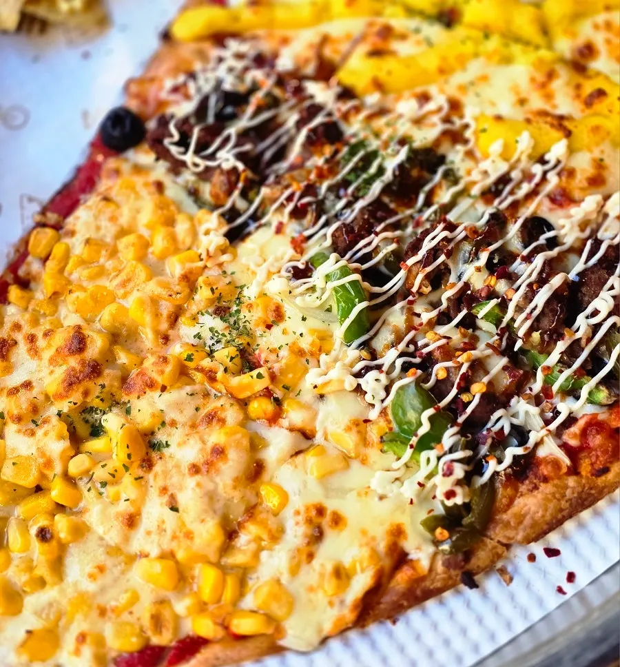 Porción de pizza con toppings de maíz dulce con queso y bacon