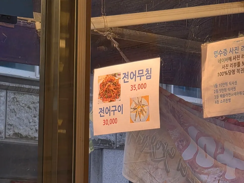 Menu board listing cockle bibimbap, nakgopsae, and sashimi sets