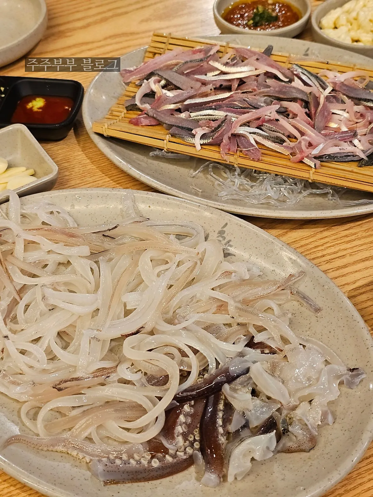 Table spread of gizzard shad sashimi and squid sashimi at Eosa Chulto Hongdae Branch