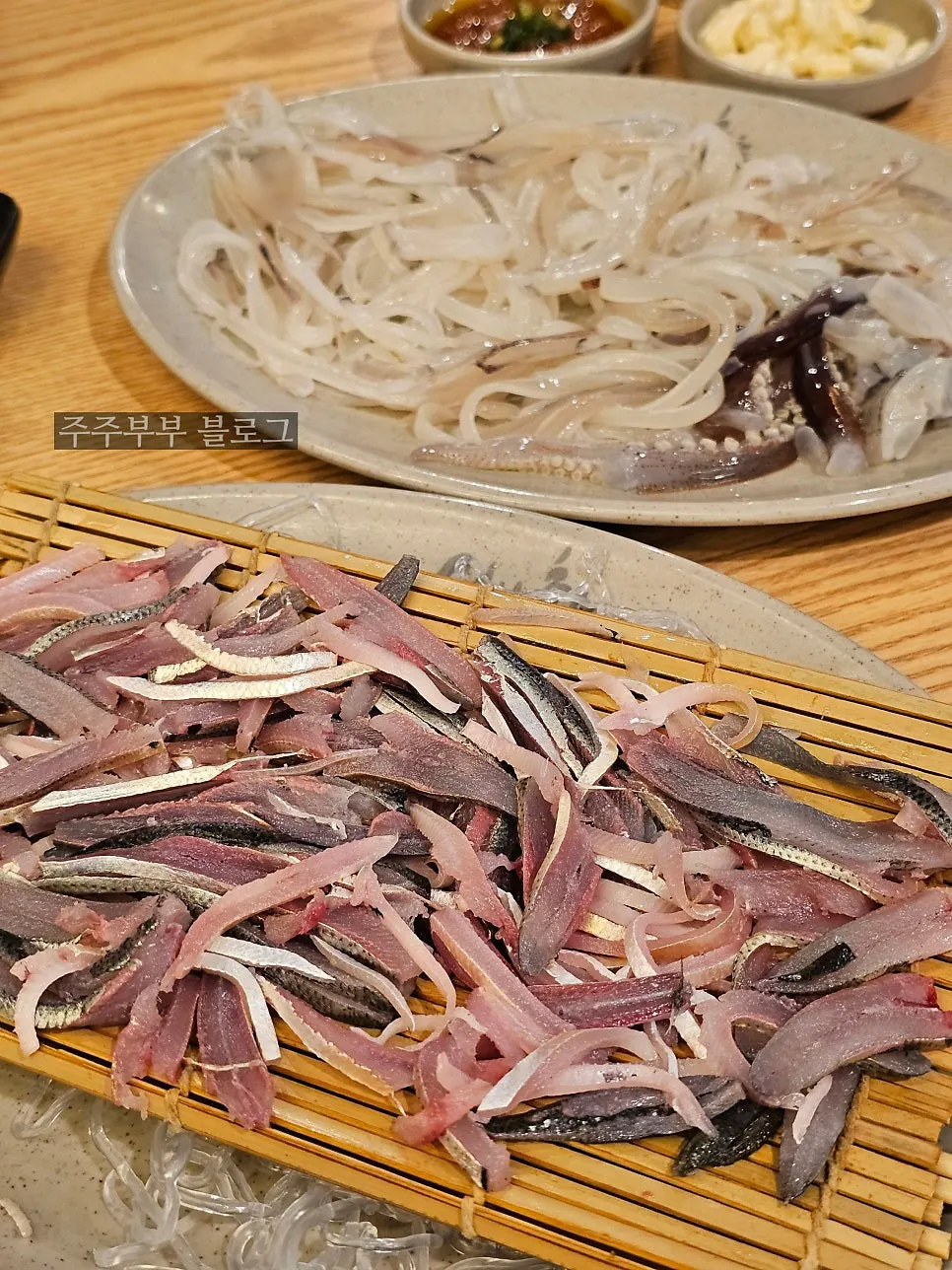 Table filled with gizzard shad sashimi, squid sashimi, and spicy stew