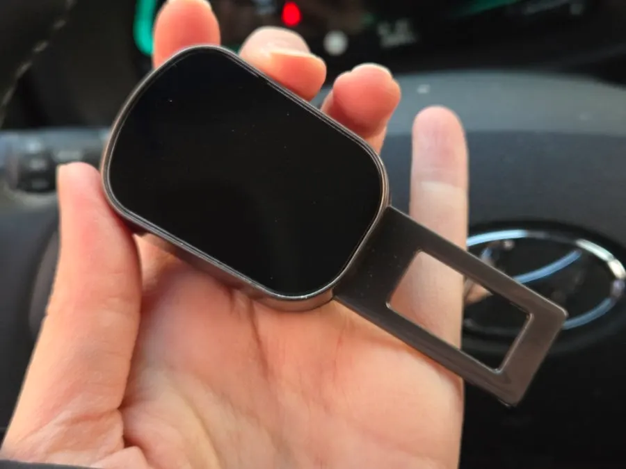 Round button on top of a seat belt extender clip