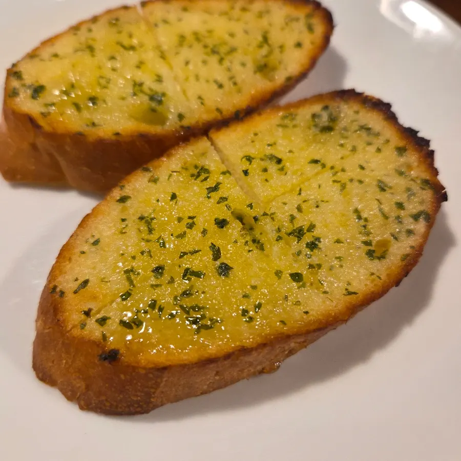 Two slices of garlic baguette served as pre-meal bread
