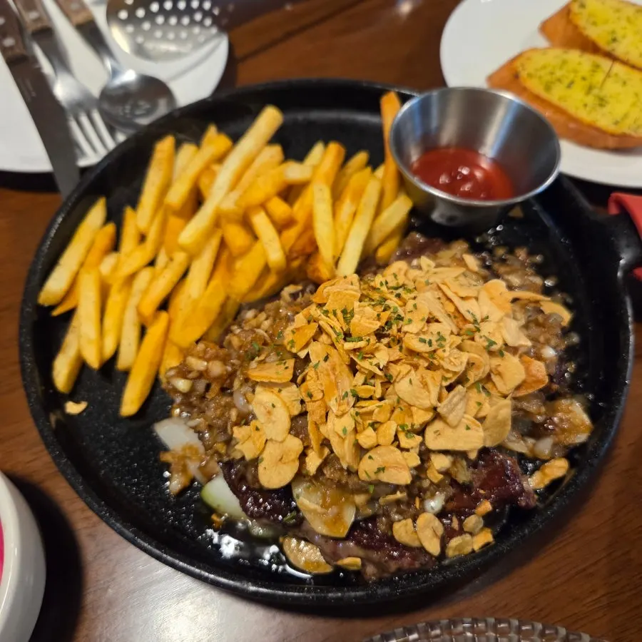 Mammoth garlic steak and fries served on an iron plate