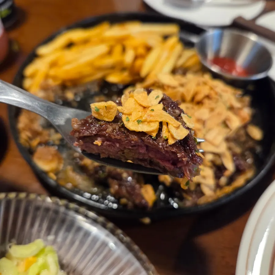 A piece of steak topped with garlic flakes