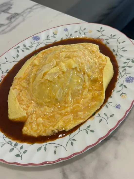 Darak omurice with the egg split open over the rice