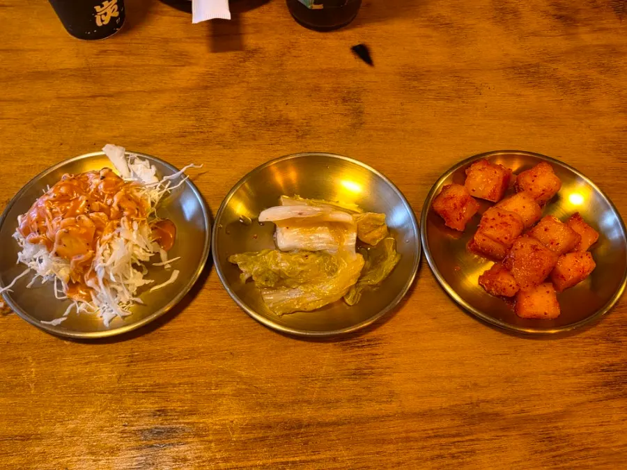 Side dish spread with cabbage salad, white kimchi, and diced radish kimchi