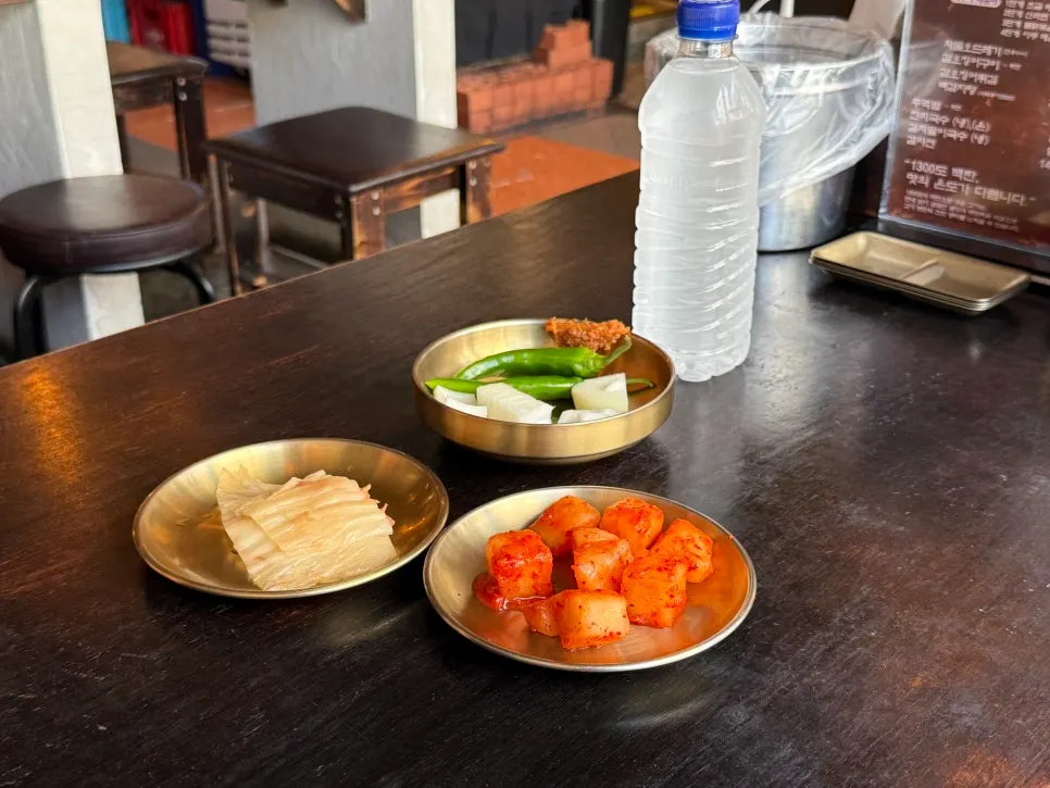 Table of side dishes: kkakdugi, peppers, onion, and baek-kimchi