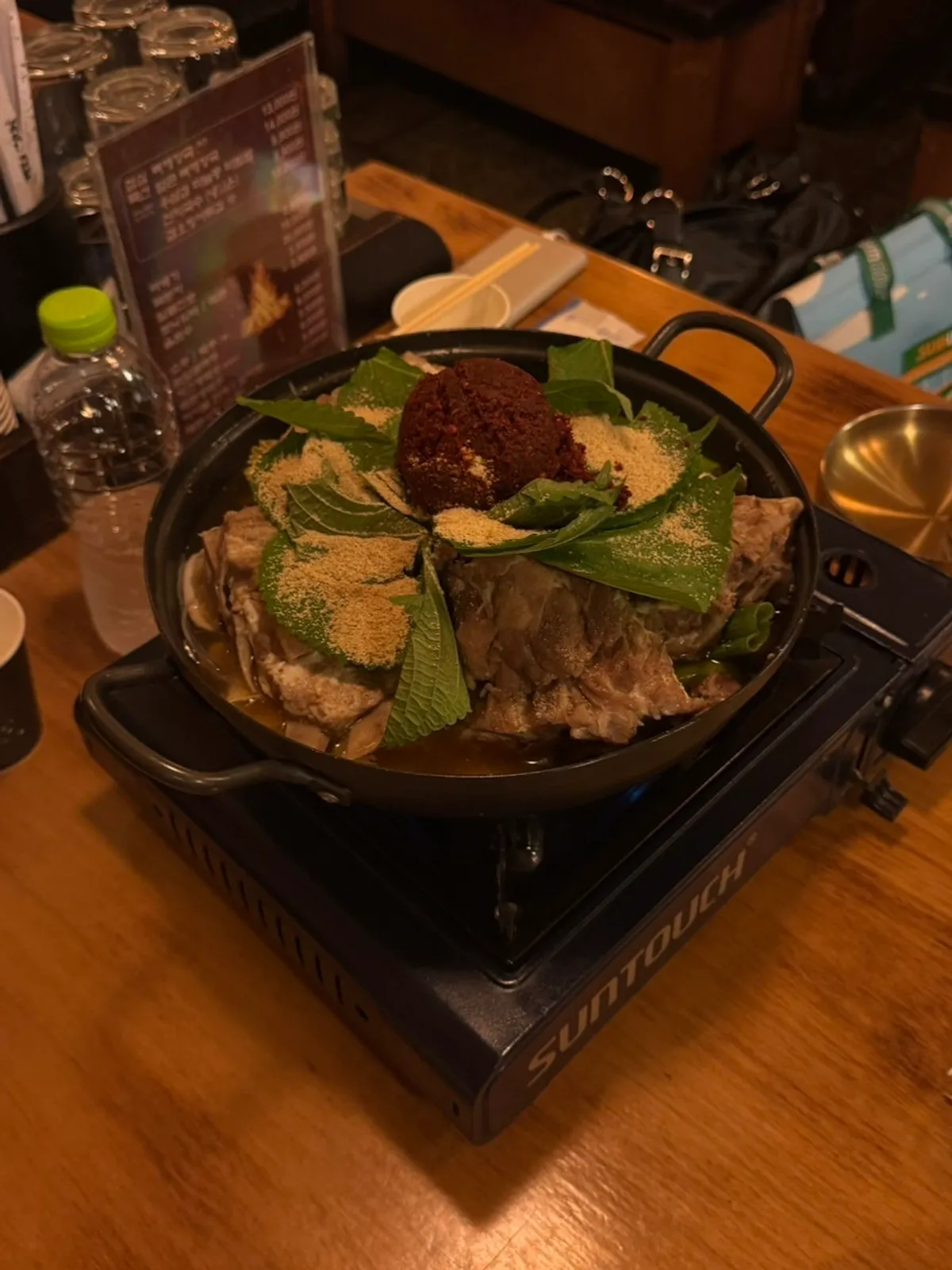 A pot of ppyeo gamjatang topped with whole green onion and perilla powder