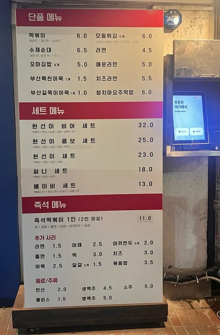 입구에 걸린 큰 메뉴판과 공중전화 모양 키오스크