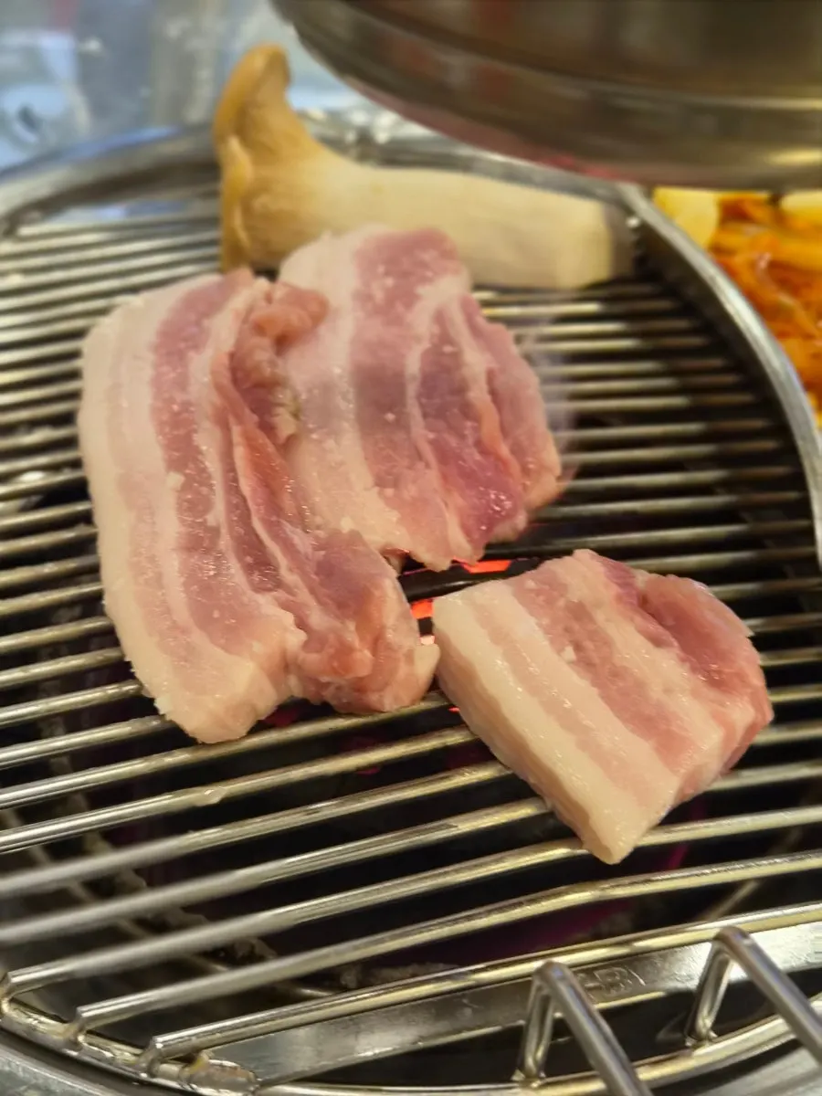 Pork belly cooking on the pan over the charcoal fire