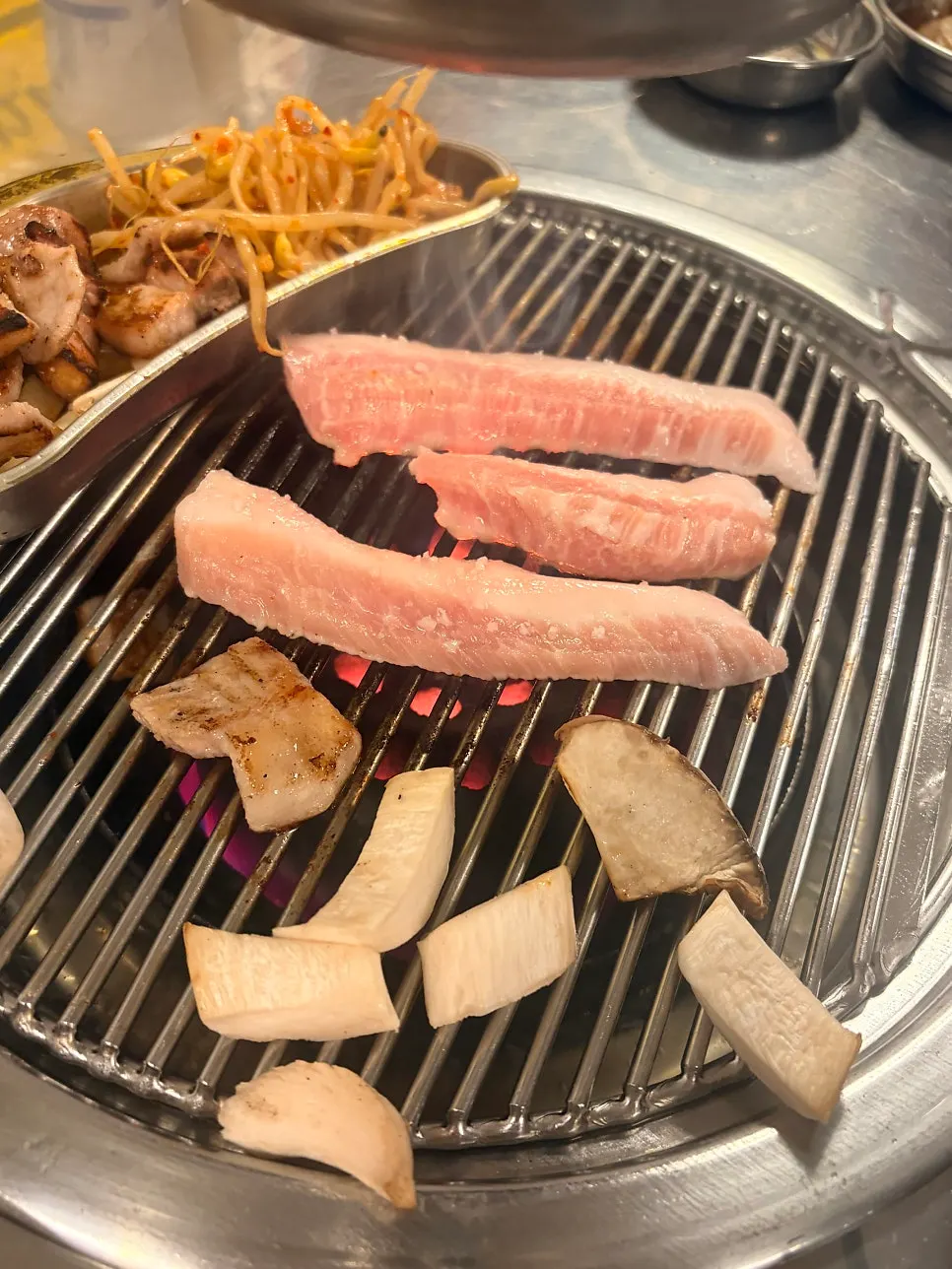 Pork jowl grilling over charcoal