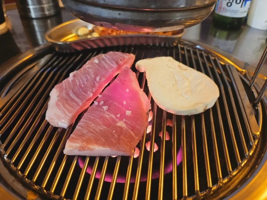 Pork jowl cooking on the charcoal grill