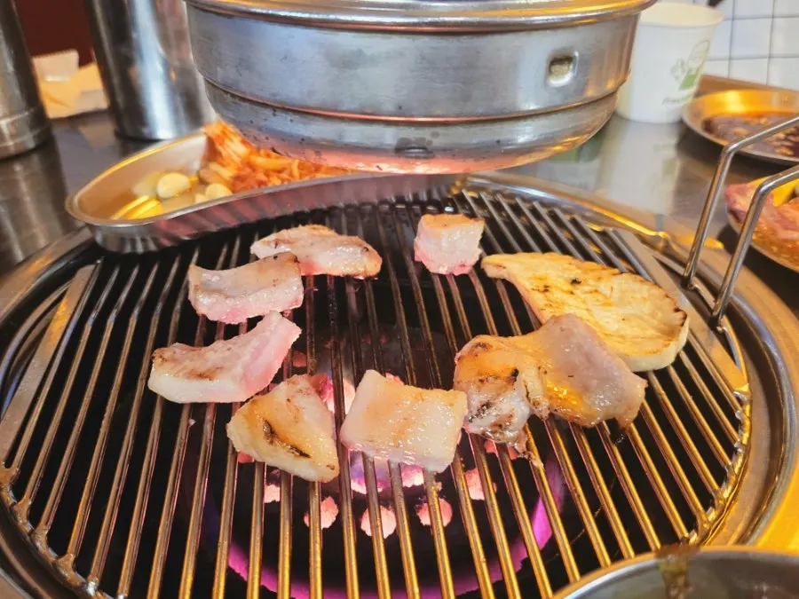 Meat grilling over the central charcoal fire