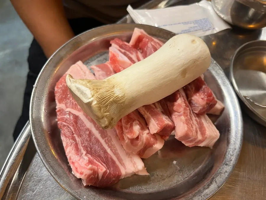 Pork belly placed on a charcoal grill grate