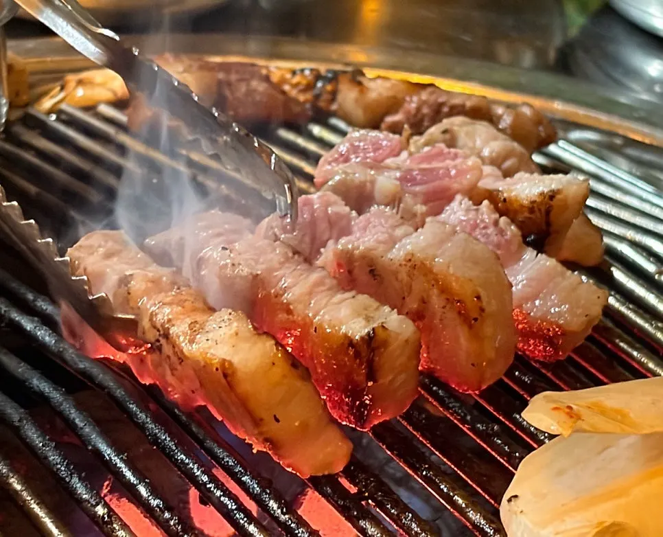 Pork belly turning golden brown over the charcoal fire