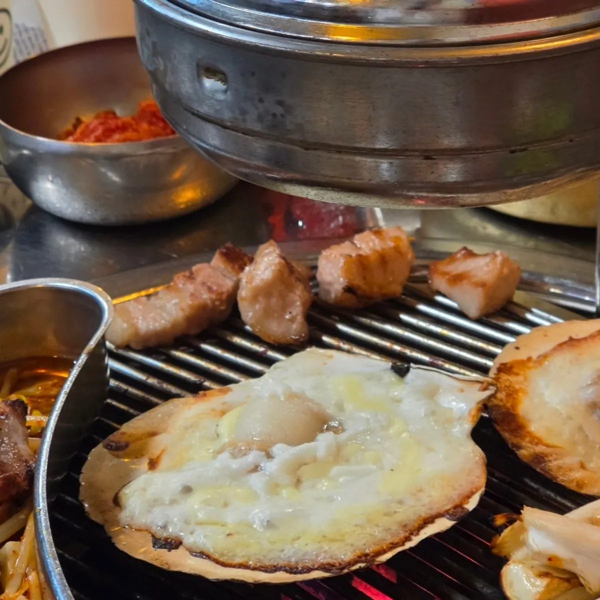 Cheese-topped scallops grilling beside the meat