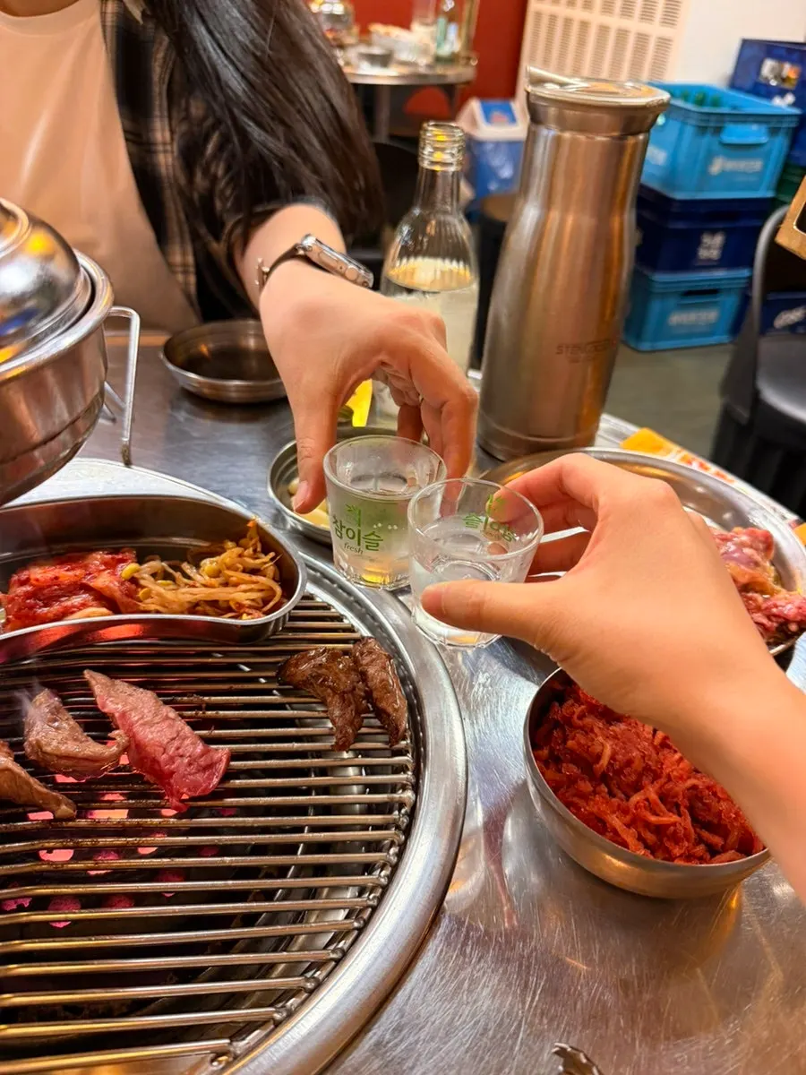 A glass of soju alongside the meat