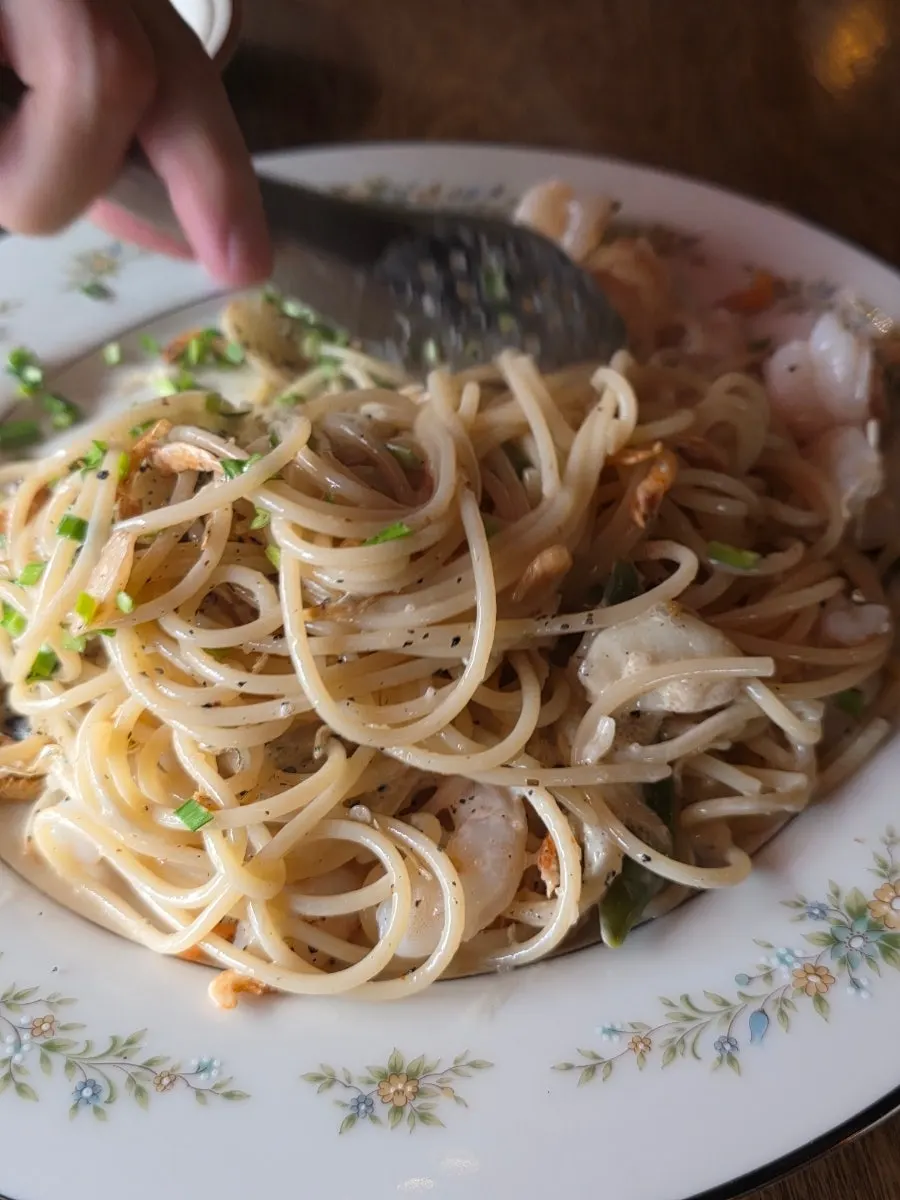 Fork lifting up noodles from the oil pasta