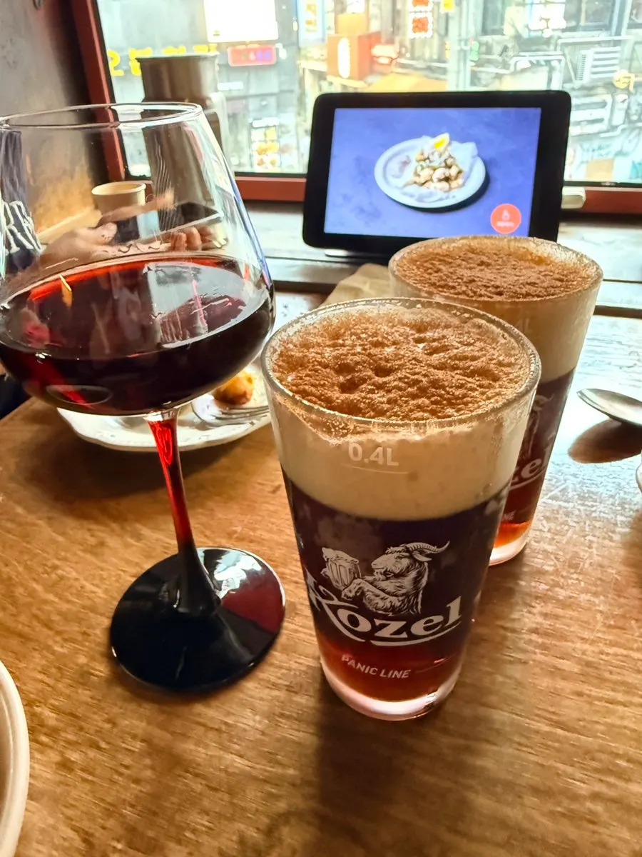 Kozel Dark dusted with cinnamon powder next to a glass of house wine