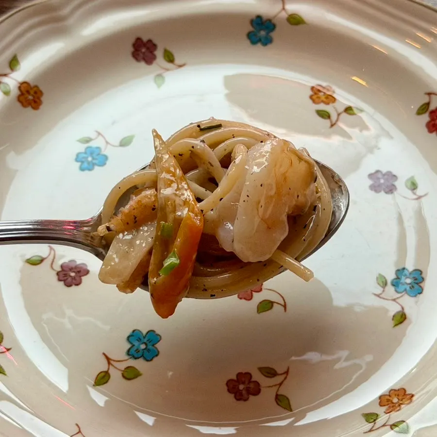A bite of oil pasta topped with chili, garlic, and shrimp