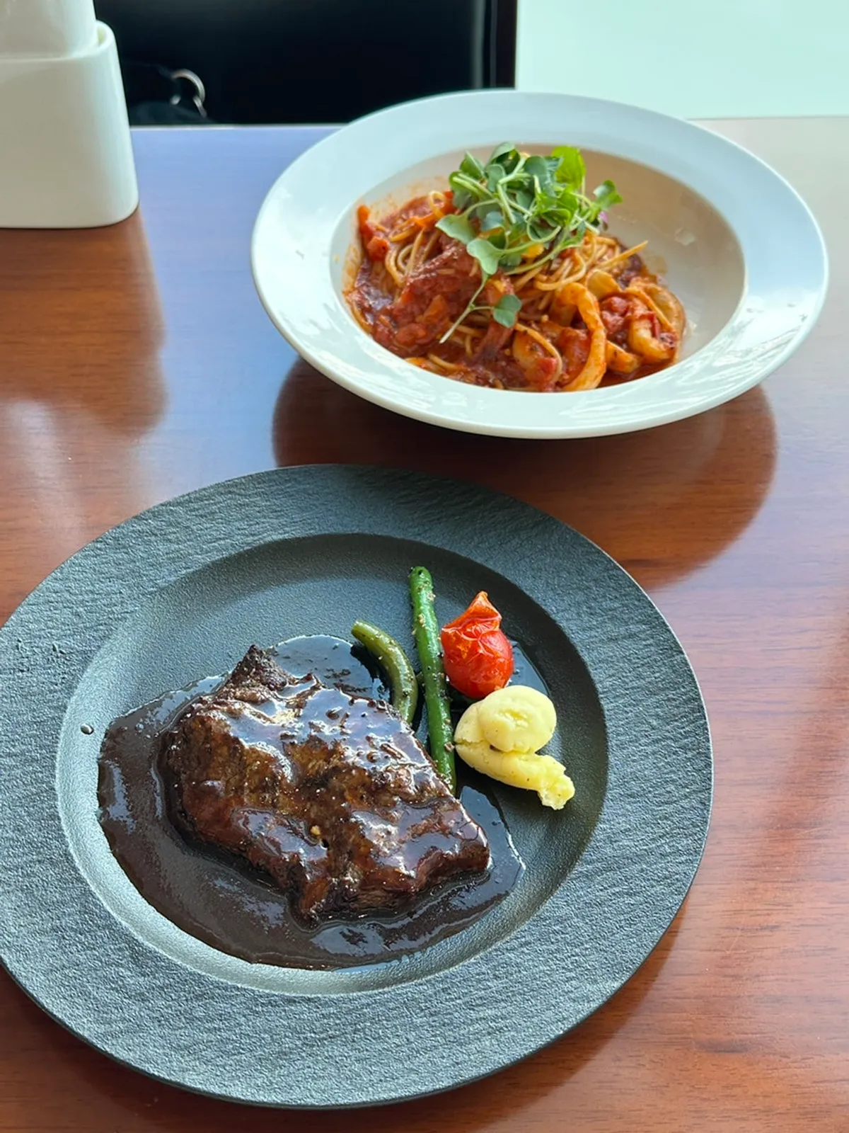 Table with steak, pasta, and buffet plates together