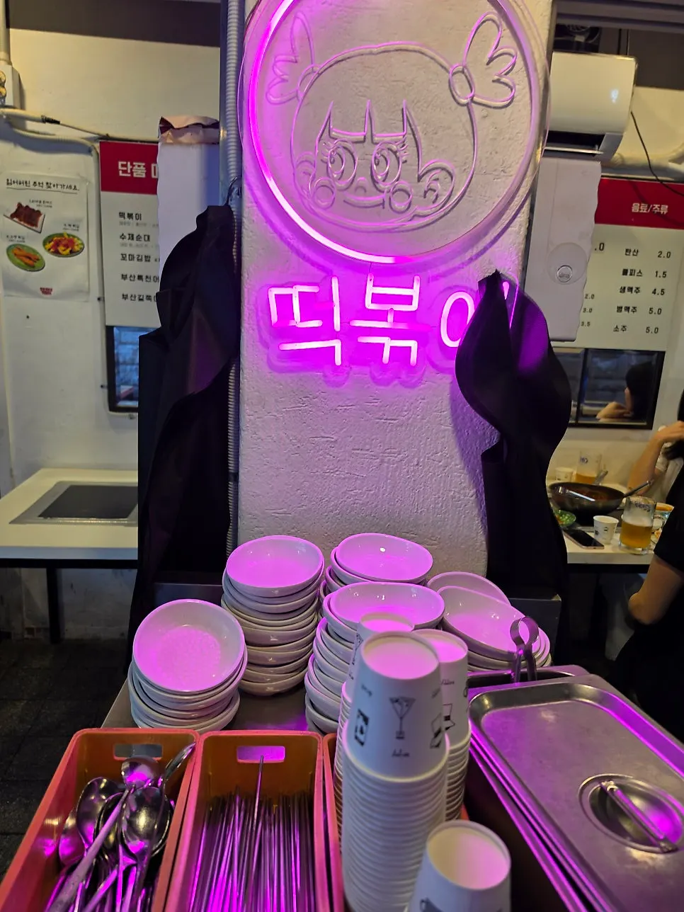 Pink tteokbokki neon sign and self-service bar