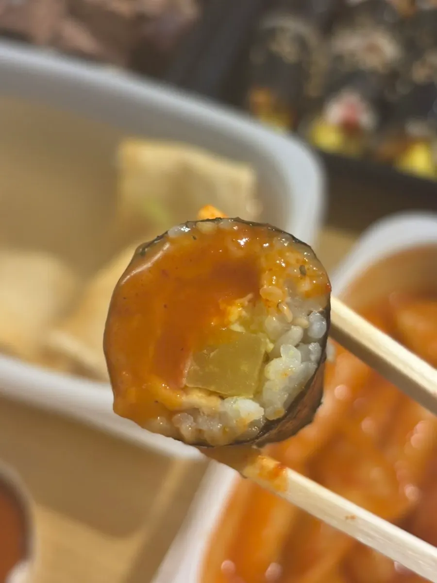 Mini gimbap dipped in tteokbokki sauce