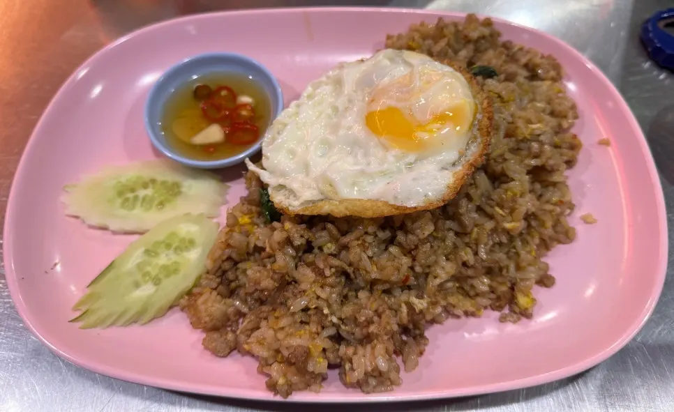 Plate of pad kra pao moo sap topped with a fried egg