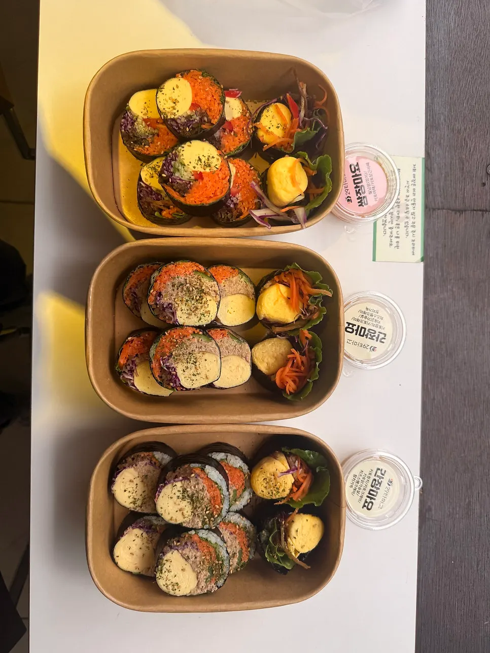Three gimbap rolls packed in takeout containers