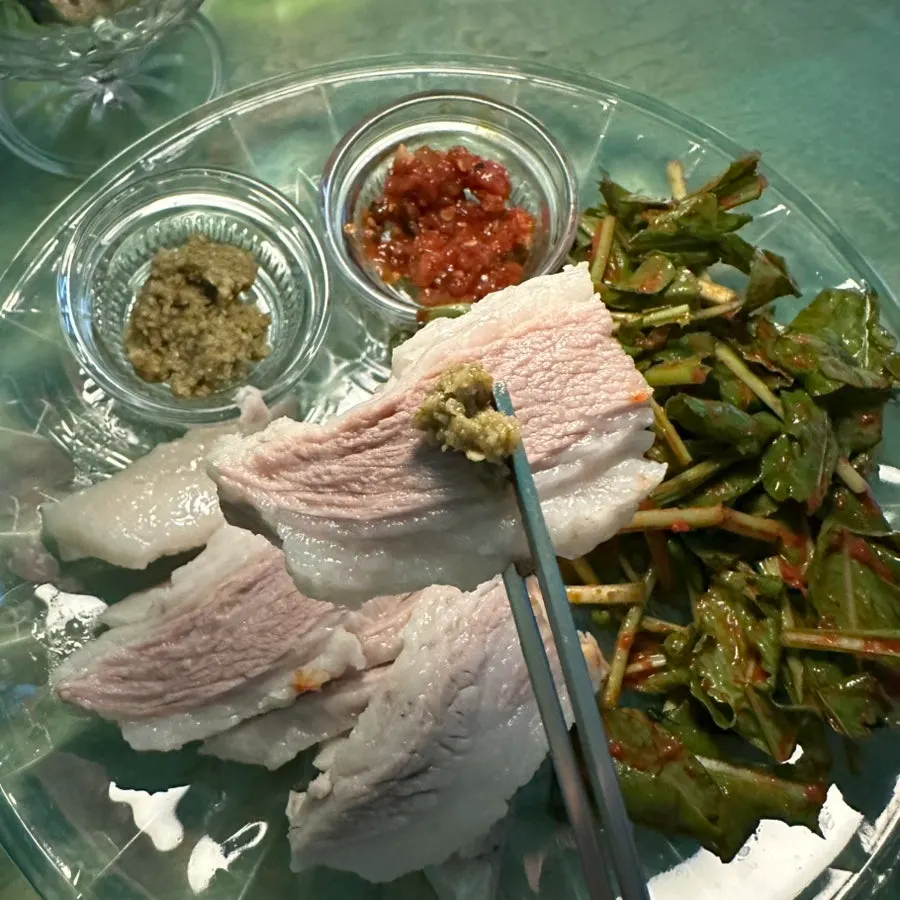 A slice of pork belly topped with rucola