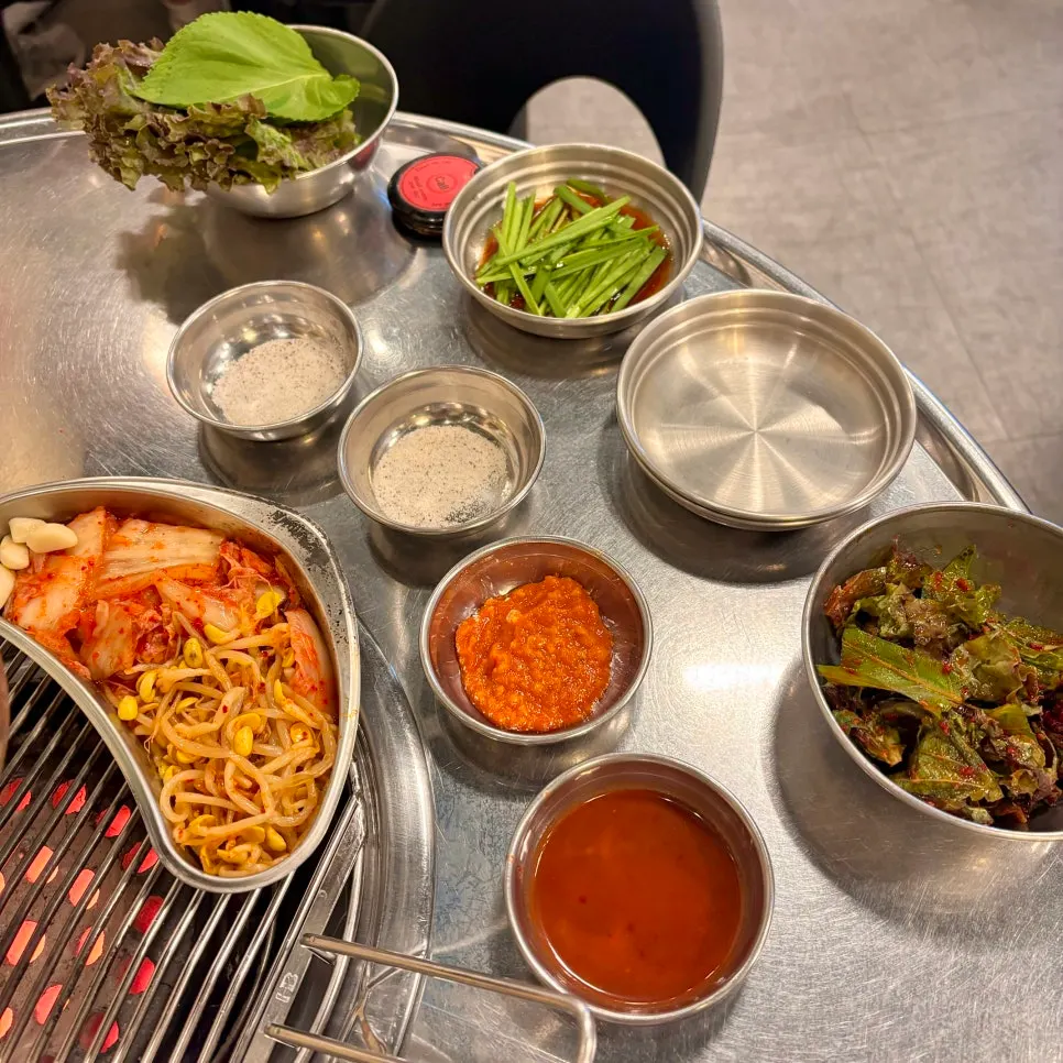 Table setting with seasoned lettuce, chives, kimchi, and bean sprouts