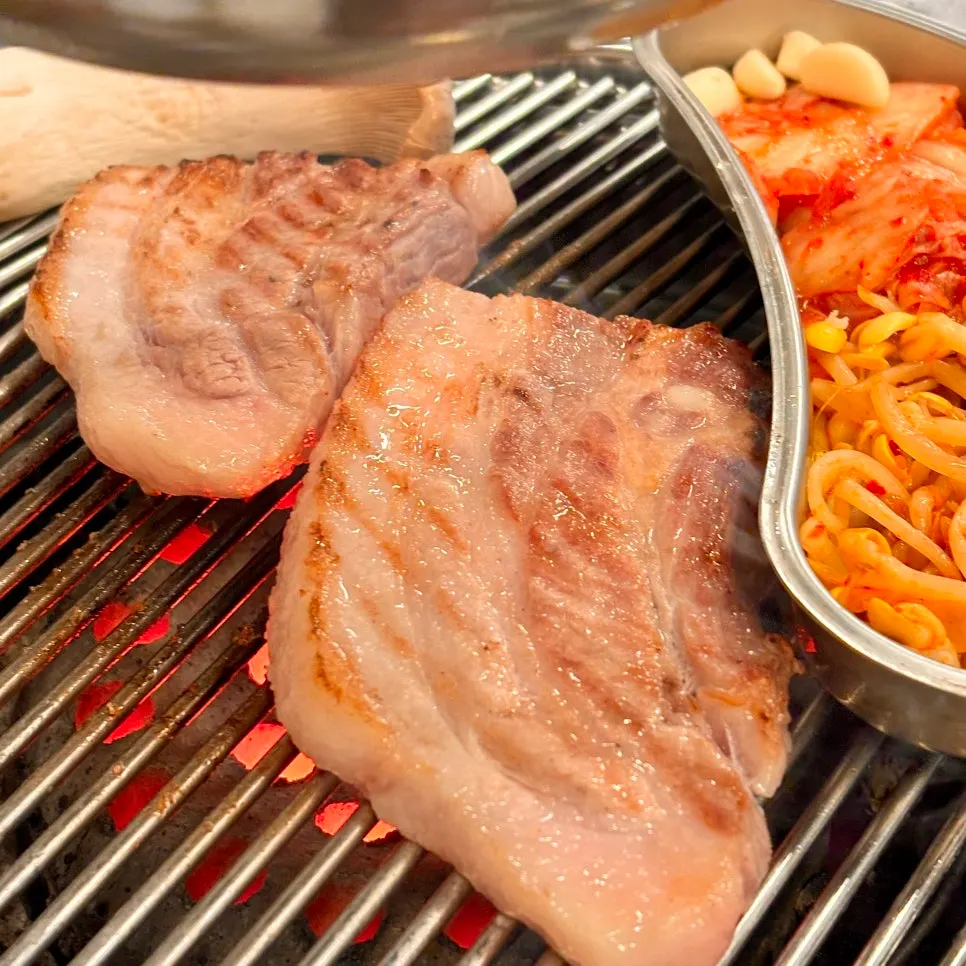 Pork belly turning golden brown on the charcoal grill