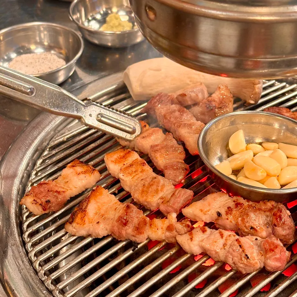 Garlic grilling alongside pork belly on the charcoal