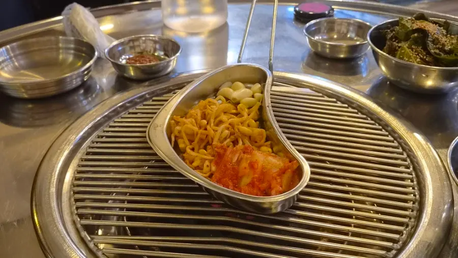불판 위에 올린 콩나물과 김치, 마늘