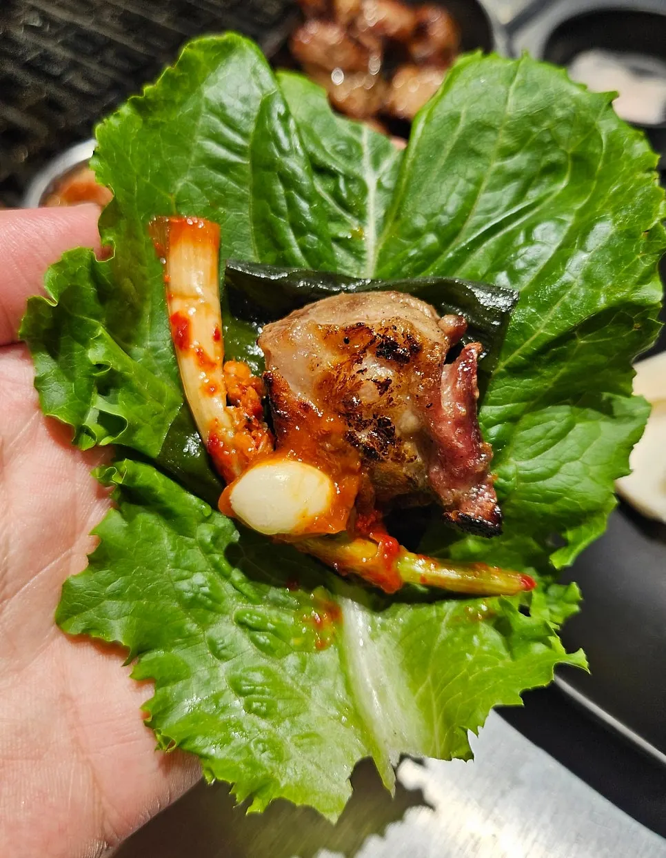 A wrap with meat and green onion kimchi on lettuce