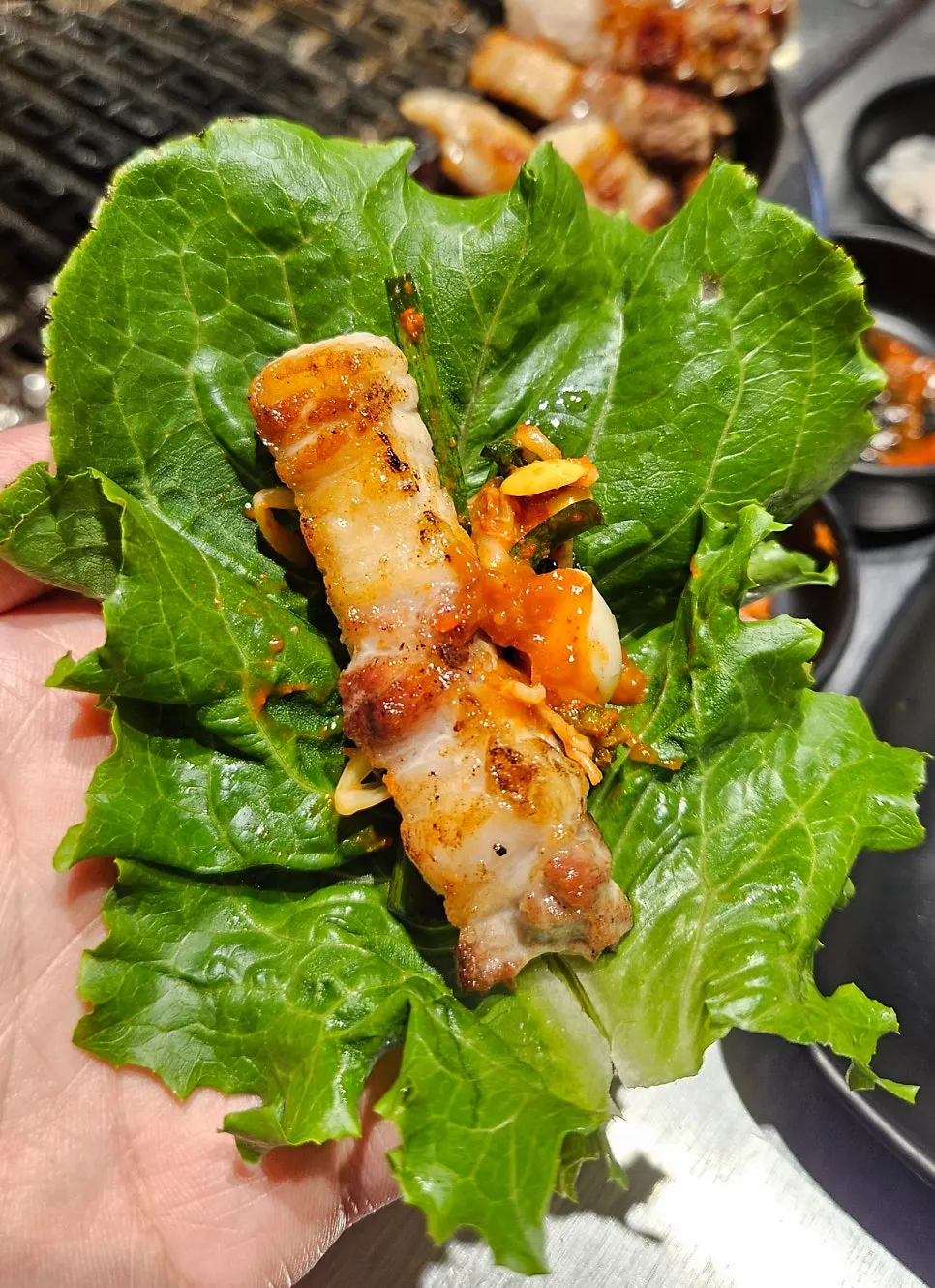 A wrap of pork belly with green onion kimchi
