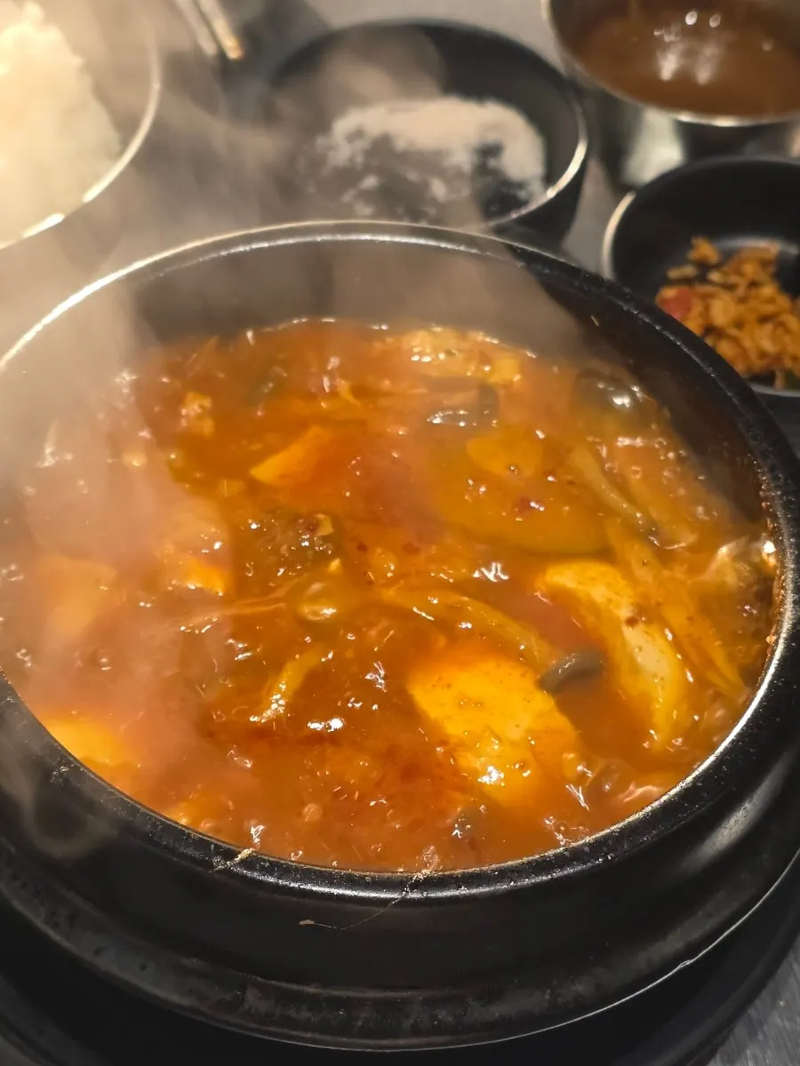 Spicy soondubu jjigae bubbling in an earthenware pot