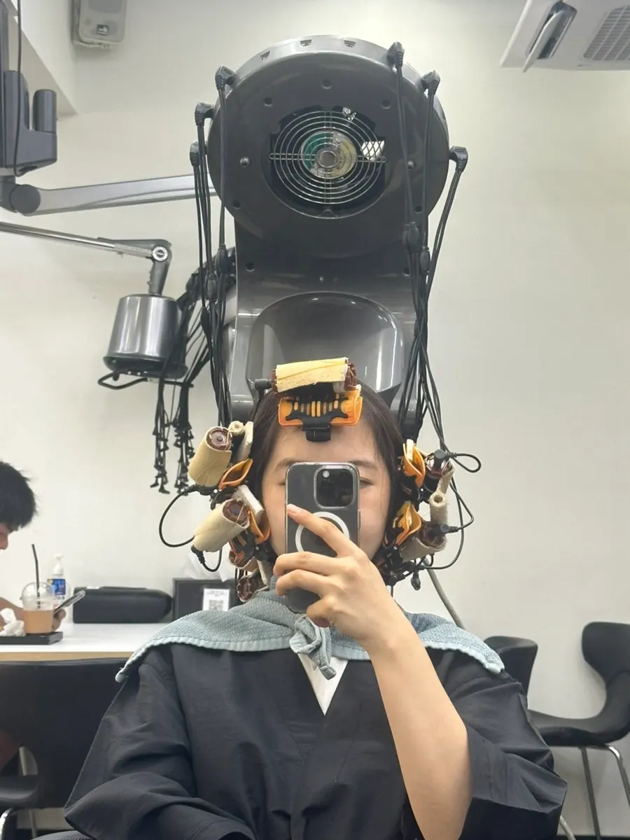 열펌 기기로 컬을 잡는 시술 장면