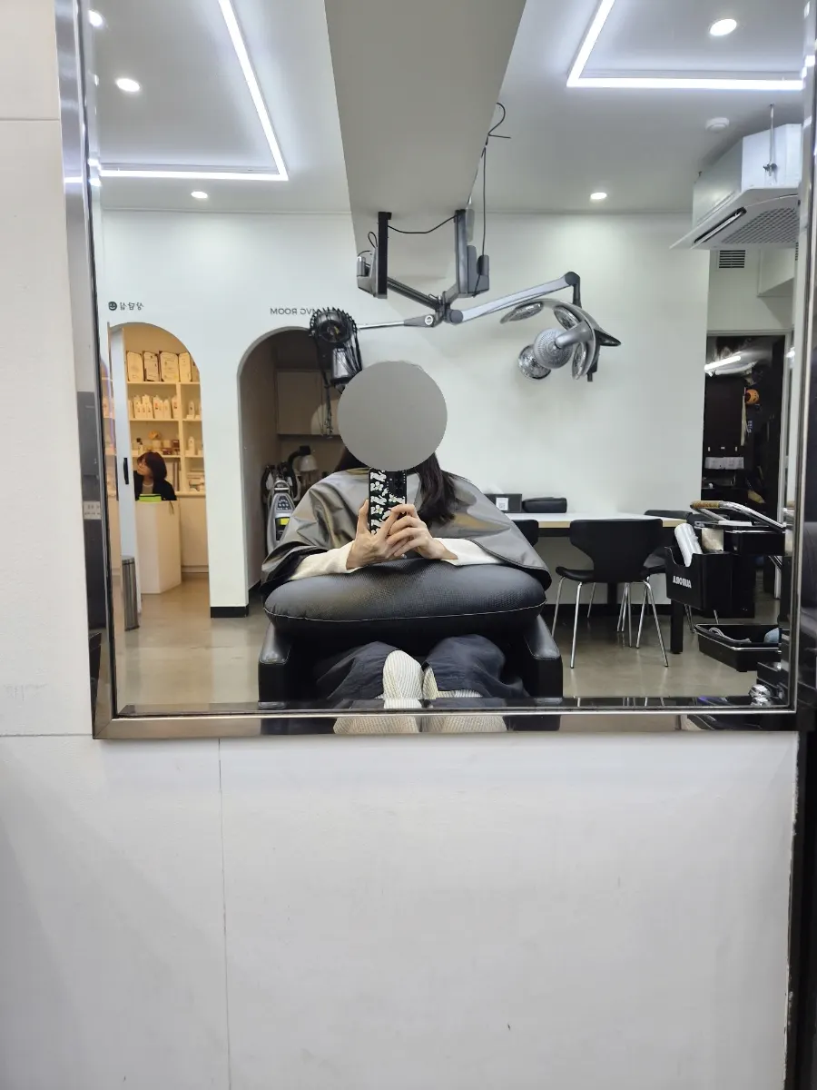 坐在美发店椅子上照镜子的施术前模样