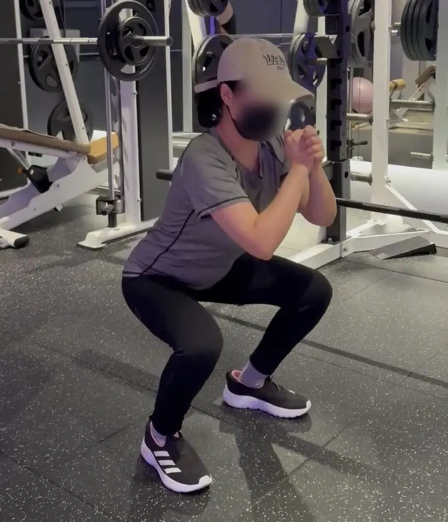 Squat form being corrected by the trainer