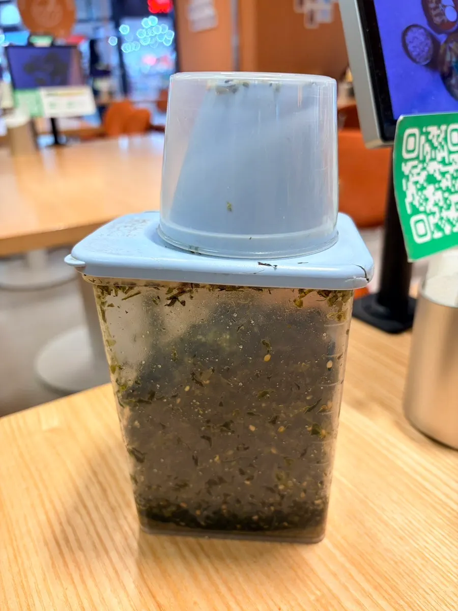 A container of seaweed flakes next to the kiosk