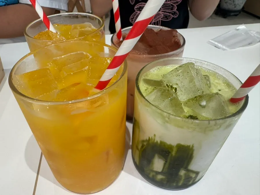 Three drinks: matcha latte, chocolate latte, and orange juice