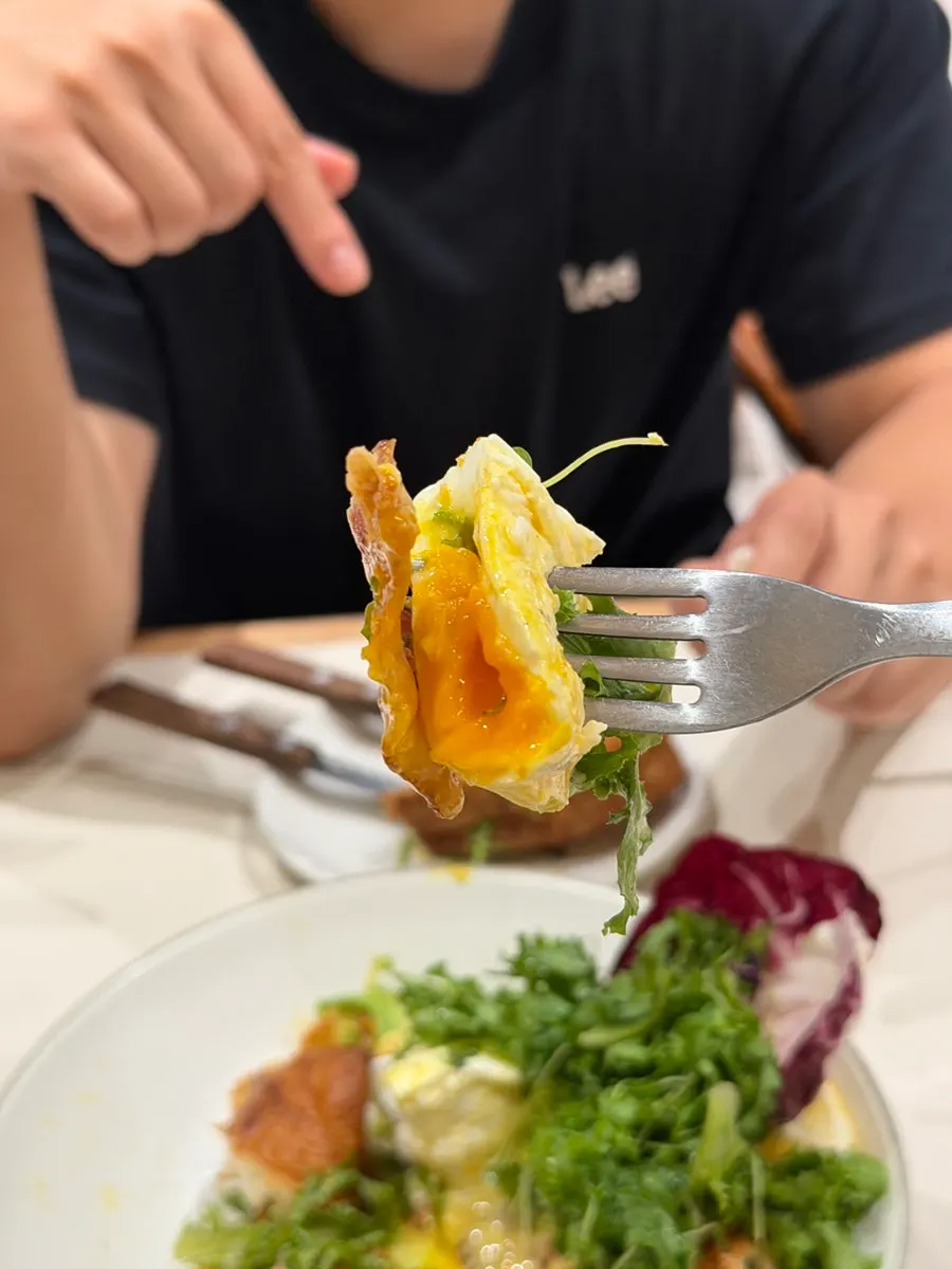 A bite combining bread, bacon, and vegetables