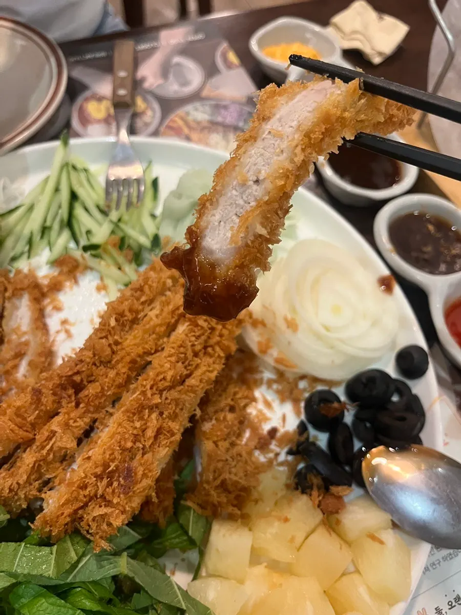 소스에 찍은 바삭한 돈까스 조각