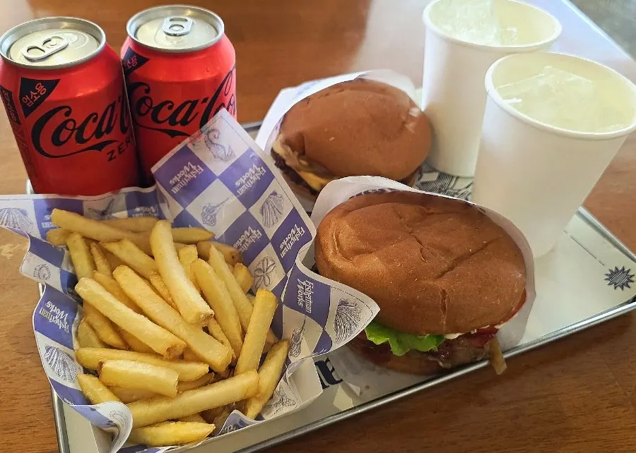 Two burgers, fries, and cola set on the table