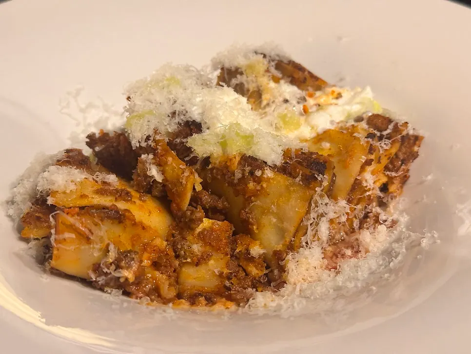 A forkful of lasagna showing its layers and ragù sauce