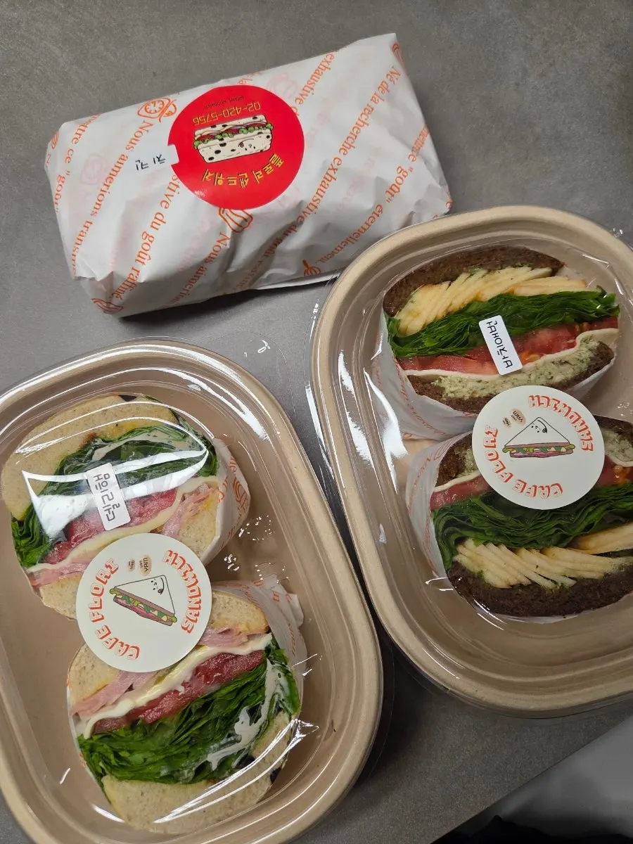 Three sandwiches wrapped in boxes and paper