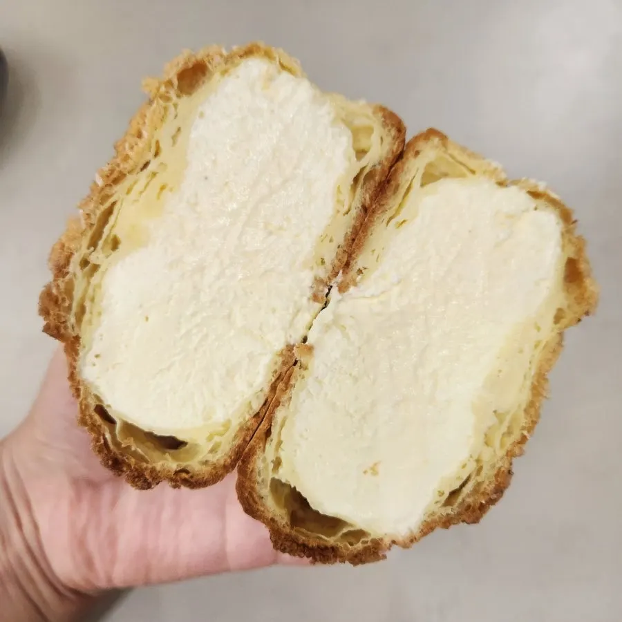 Halved frozen plain choux showing generous cream filling