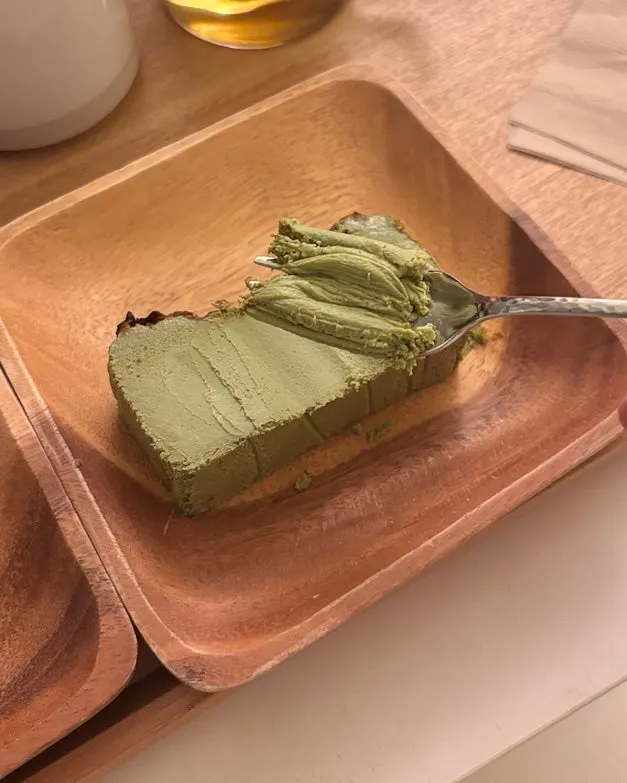 Dense matcha Basque cheesecake lifted up with a fork
