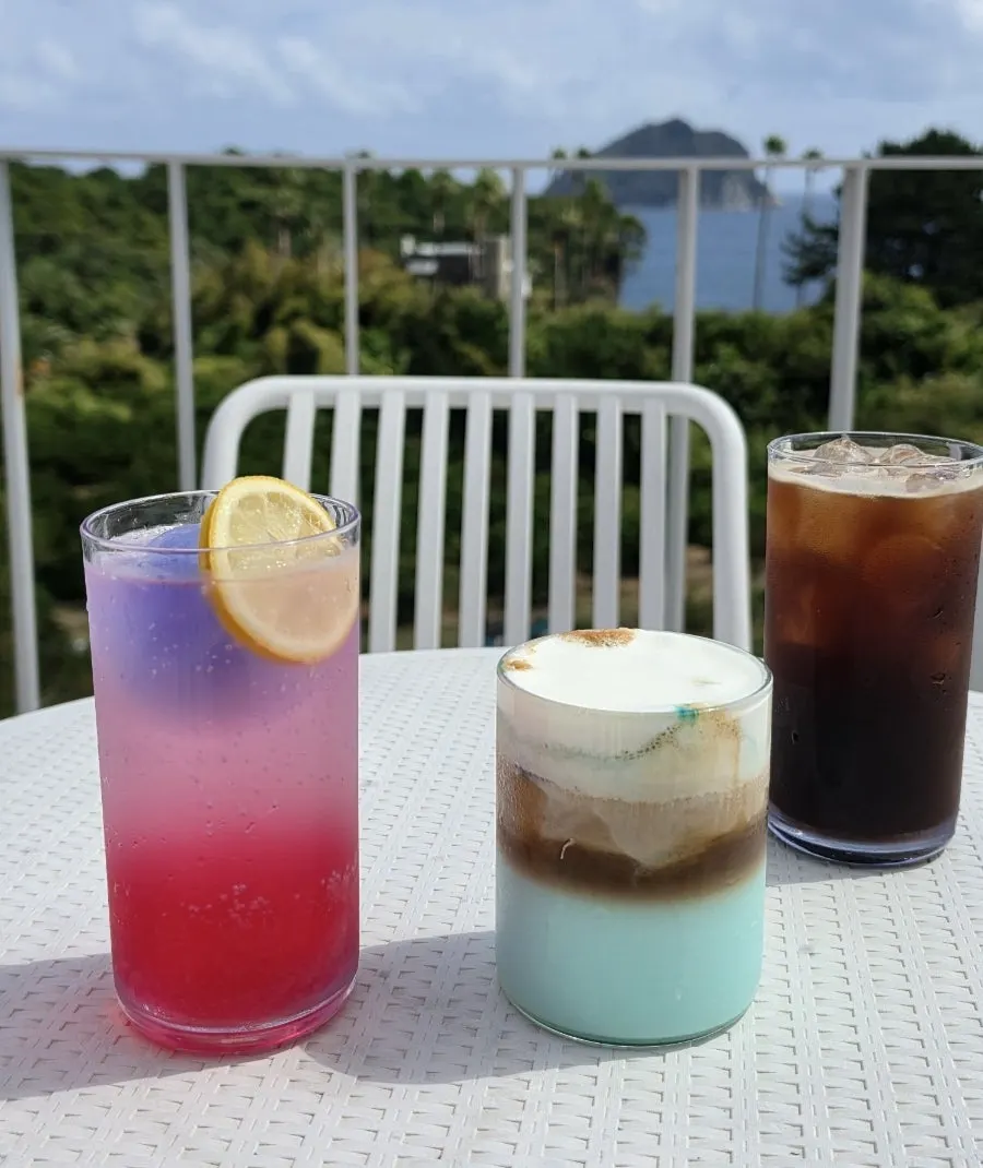 Three drinks lined up with the sea in the background